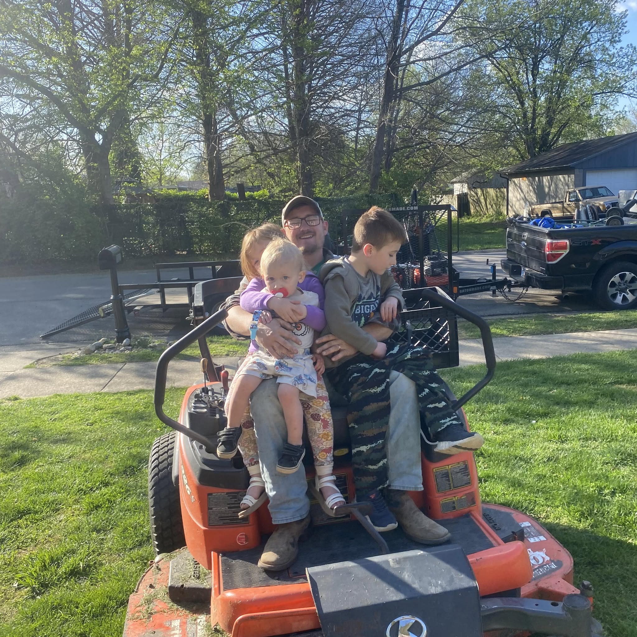 Josh Sauer with his children on a lawn mower