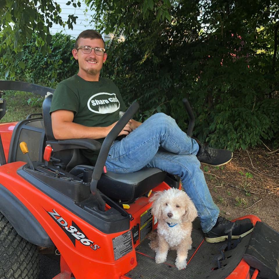Josh Sauer on a mower with his dog